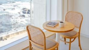 a table and chairs with a book and a cup of coffee at Donghae Badadam Ocean View Spa Pension in Donghae