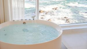 a bath tub with water coming out of it next to a window at Donghae Badadam Ocean View Spa Pension in Donghae