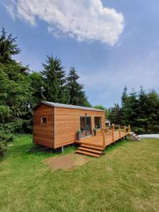 a small cabin with a deck on a grass field at TINY Klíny in Klíny