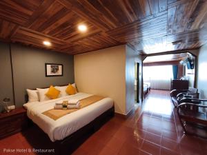 ein Schlafzimmer mit einem großen Bett und einer Holzdecke in der Unterkunft Pakse hotel & Restaurant in Pakse