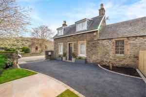 an exterior view of a stone house with a driveway at Grange Cottage in Galashiels