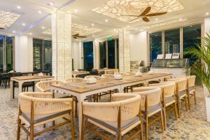 a dining room with tables and chairs and windows at Avyanna Gulhi Beach Hotel in Gulhi