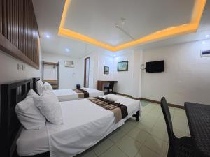 a hotel room with two beds and a tv at White Beach Resort Bar & Restaurant in Puerto Galera