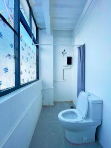 a white bathroom with a toilet and a window at Moalboal Seaside Resort in Moalboal