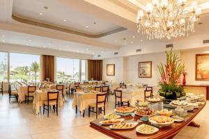 a dining room with tables and chairs and a chandelier at Hotel Presidente in Mar del Plata