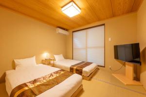 a room with two beds and a flat screen tv at Spacious Kyoto Machiya - Goemon Bath - 4BR in Kyoto