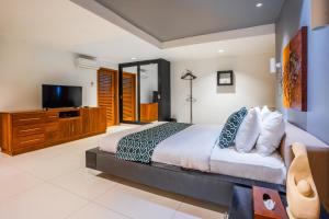 a bedroom with a bed and a flat screen tv at Hening Jimbaran in Jimbaran