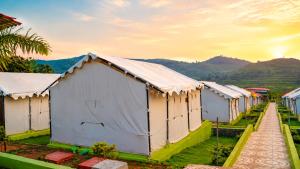a row of white buildings with mountains in the background at Sumitel Araku Mount View Camping Resort in Sunkarimetta +7 photos