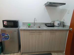 a kitchen with a sink and a microwave and a refrigerator at Hailey's Place Unit 3 in Bacolod