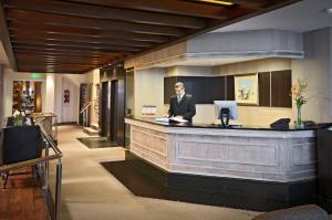 a man standing at a reception desk in a lobby at Hotel Presidente in Mar del Plata