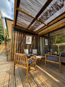 a wooden deck with benches and a pergola at La Buissonnière Lodges in Chisseaux