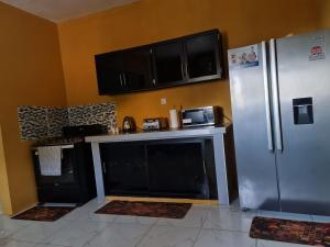 a kitchen with black cabinets and a stainless steel refrigerator at Round Hill View Heights in Pedro Cross