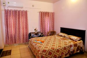 a bedroom with a bed and a chair and curtains at Alleppey La Casa in Alleppey