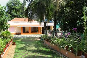 a garden in front of a house with palm trees at Alleppey La Casa in Alleppey