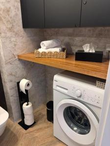 a bathroom with a washing machine and a shelf with towels at Apartament SANOVA 55 in Sanok