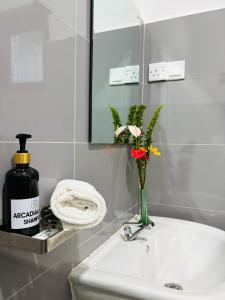 a bathroom sink with a vase with flowers in it at Arcadiaa Hotel in Anaulundawa +34 photos