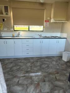 a kitchen with white cabinets and a stone floor at Beaufort Lake Caravan Park in Beaufort +42 photos