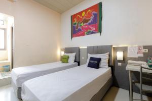 a hotel room with two beds and a desk at Urbanview Hotel Delima 101 Syariah in Serang