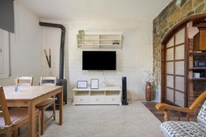 a living room with a table and a tv on a wall at Villa Sueños Piscina Costa Dorada in Calafell