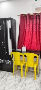 a yellow table and two chairs next to a red curtain at Hotel Royal Orbit in Rajauli