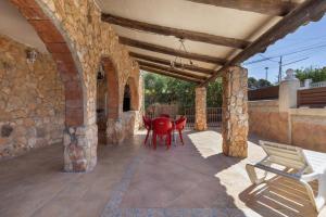 an outdoor patio with red chairs and a table at Villa Sueños Piscina Costa Dorada in Calafell