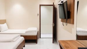 a room with two beds and a flat screen tv at Hotel Volga 2 in Mumbai