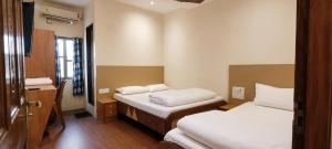 a hotel room with two beds and a mirror at Hotel Volga 2 in Mumbai +4 photos