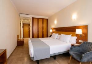 a bedroom with a large white bed and a chair at Hotel Córdoba Centro in Córdoba