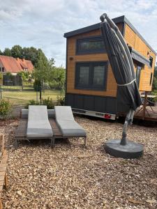a tiny house with two chairs and an umbrella at KE-Tiny- Siedlung Haus Paulchen in Oerlenbach