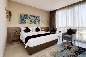 a bedroom with a large bed and a chair at Sunday Hotel Antero Jababeka in Cikarang