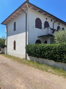 a white building with arched windows and a dirt road at Sweet home Torre del lago in Torre del Lago Puccini