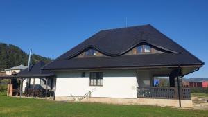 a large white house with a black roof at Pensiunea Mușata Bucovinei in Vama