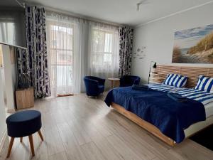 a bedroom with a bed with blue sheets and blue chairs at Maritime Apartment in Świnoujście