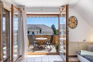a room with a balcony with a table and a clock at bleib. Boutique Fewos Bodensee in Radolfzell am Bodensee
