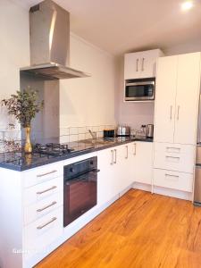 a kitchen with white cabinets and a stove top oven at The She Oak in Carterton +6 photos