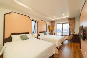 a hotel room with two beds and a television at Olong Pho Co Hotel Ninh Binh in Kỳ Vĩ