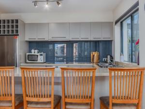 a kitchen with white cabinets and a counter with four chairs at Breakwater Views Apartment 2 Cabarita Beach in Cabarita Beach