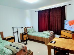 a room with two beds and a table and a tv at Goranovi House in Pleven