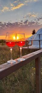 two wine glasses sitting on top of a wooden table at Glamping 4 us in Topliţa