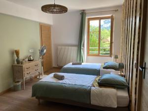 a bedroom with two beds and a window at Du Baume Au Cœur in Baume-les-Messieurs