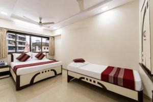 two beds in a room with a window at Hotel Kalpana Palace, Mumbai in Mumbai