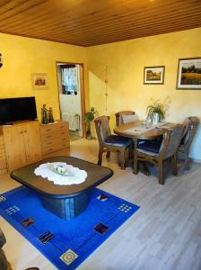 a living room with a table and chairs and a tv at Ferienwohnung Waldblick in Langenfeld