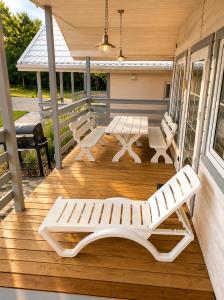 a porch with white benches on a wooden deck at Osada Pana Kraba in Jarosławiec