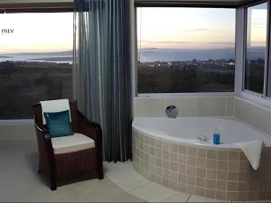a bathroom with a tub and a chair and a window at Dunestone Boutique GuestHouse in Langebaan +20 photos