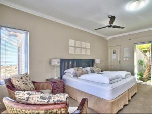a bedroom with a bed and chairs and a ceiling fan at Dunestone Boutique GuestHouse in Langebaan