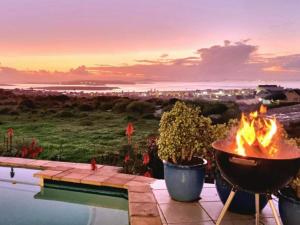 a fire pit next to a pool with a view of the ocean at Dunestone Boutique GuestHouse in Langebaan