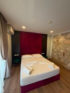 a bedroom with two beds and a stone wall at Monarch Beach in Borsh +6 photos