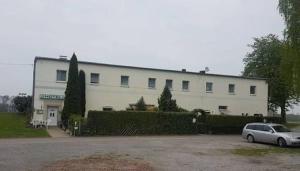 a white building with a car parked in front of it at Hotel zur Rennvahn in Dortmund