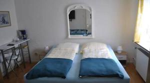 a bed with two pillows and a mirror in a room at Hotel zur Rennvahn in Dortmund