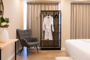 a dressing room with a white robe on a shelf and a chair at Arena Málaga Suites in Málaga